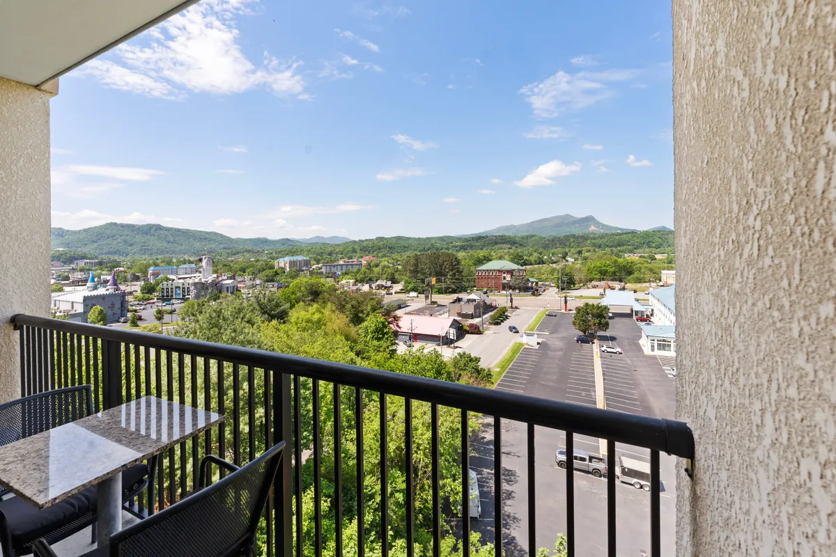 A scenic view from the balcony complete with inviting seating, expansive mountain vistas, and a clear look over the charming town below. The ambiance is peaceful and perfect for enjoying a coffee or intimate conversation.