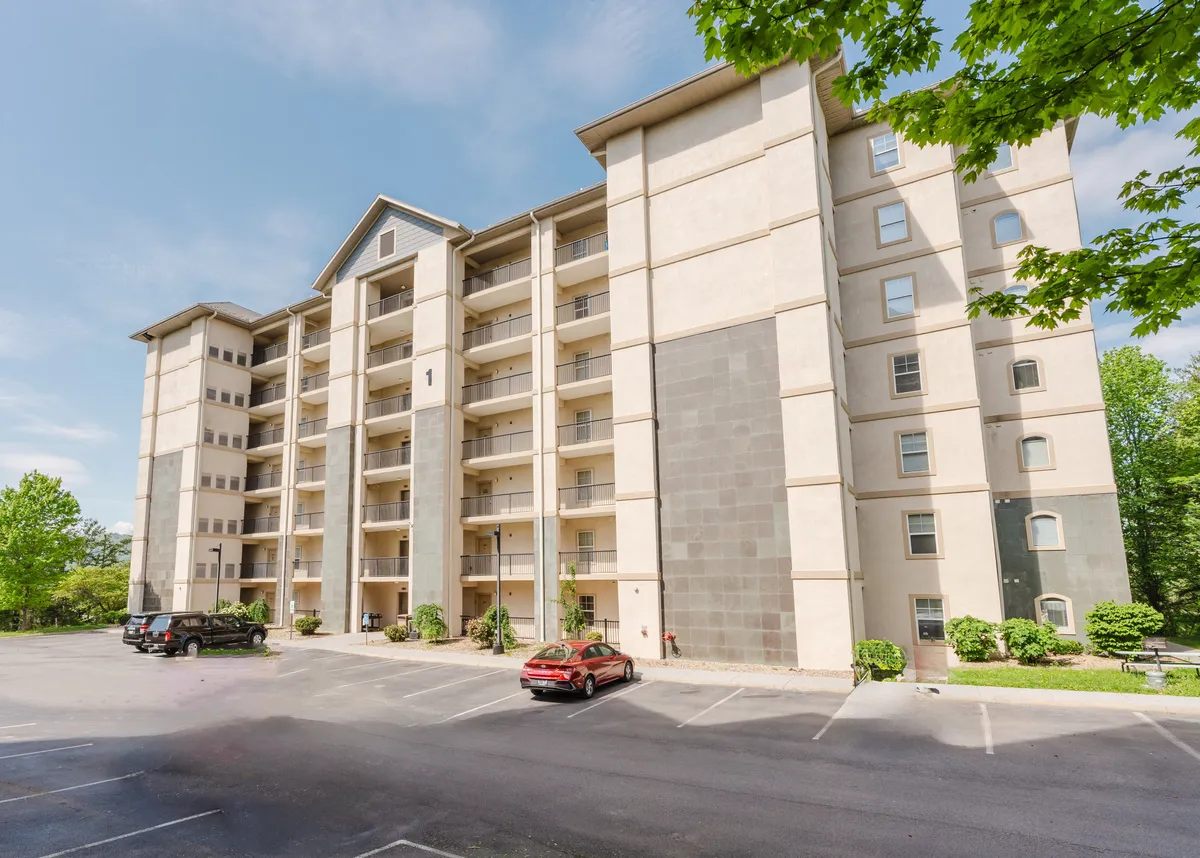 An inviting shot of the building facade with multiple balconies and lush greenery, evoking a sense of arrival and the promise of shared experiences. The balconies hint at private spaces to unwind after a day of exploration.